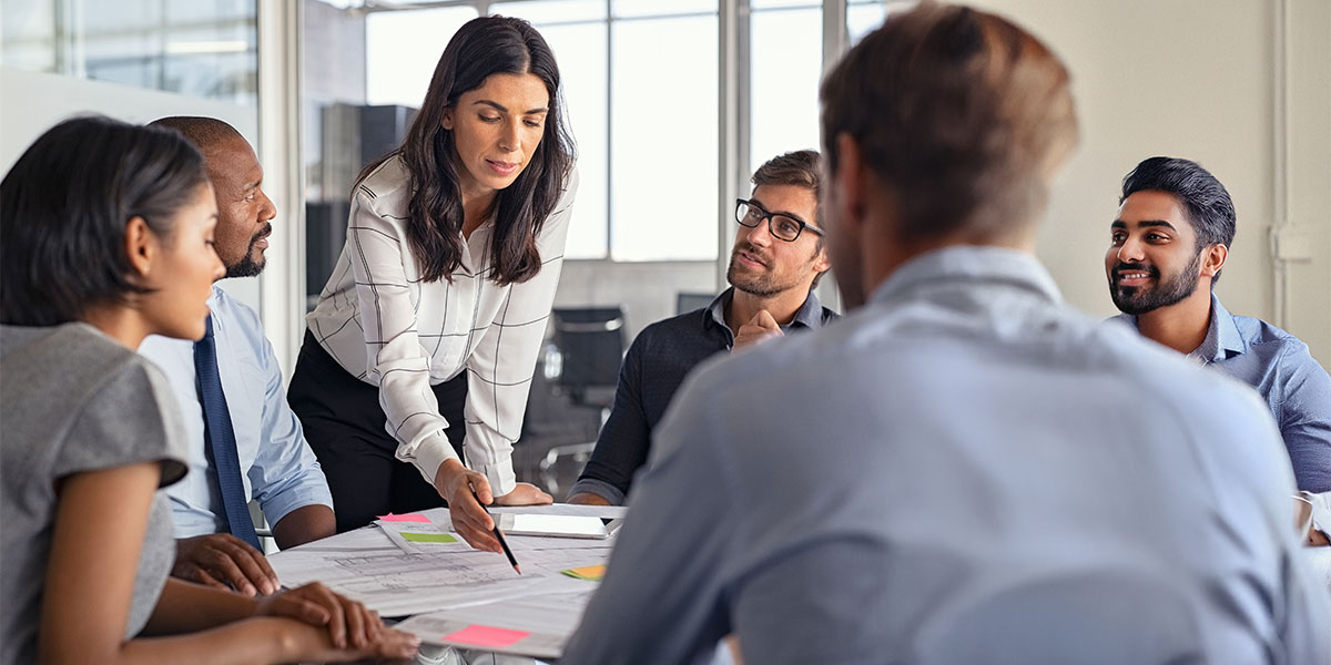 Construction professionals discuss blueprints in a group meeting.